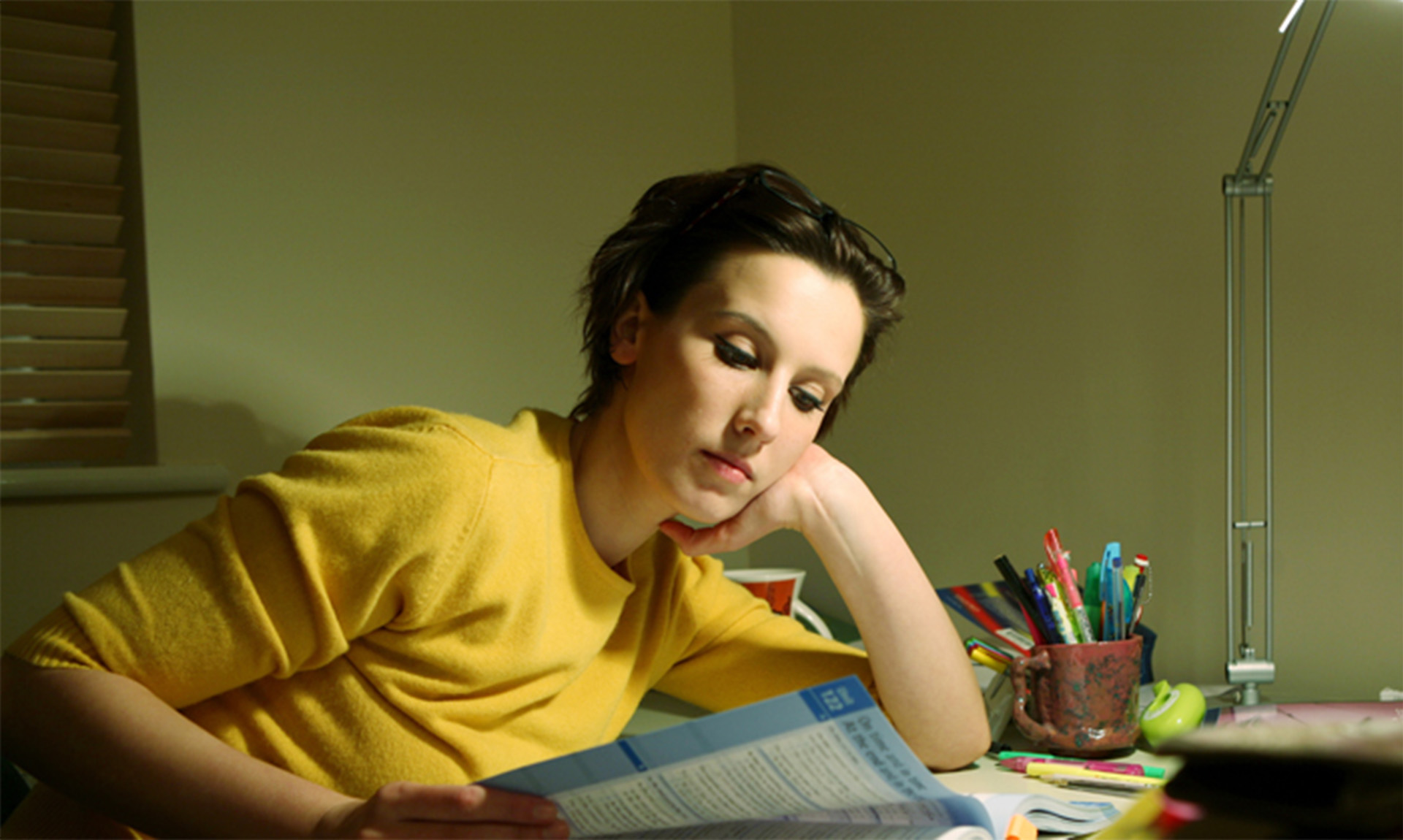 A young person in a yellow shirt reads.