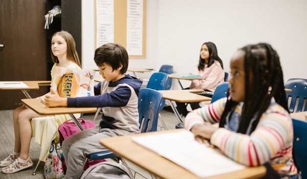 Elementary school students listen to a lesson while one child reads
