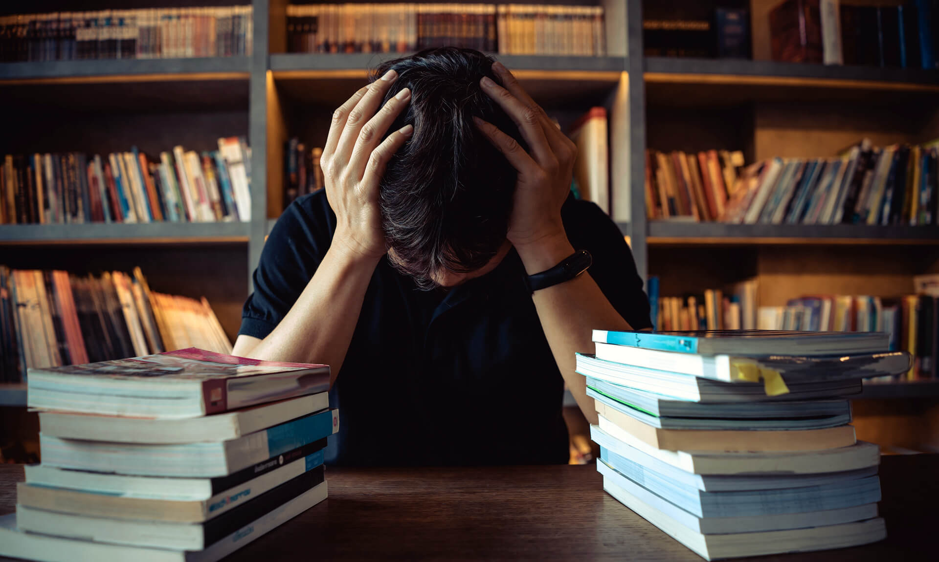 Tired man under mental pressure while reading book in library.