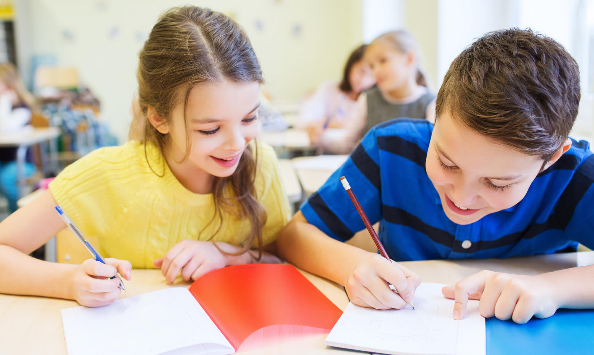 Two students completing a writing assignment in the classroom.