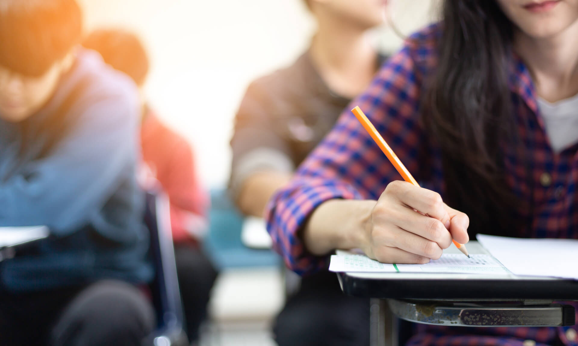 Class of high school students seated at desks taking exam.