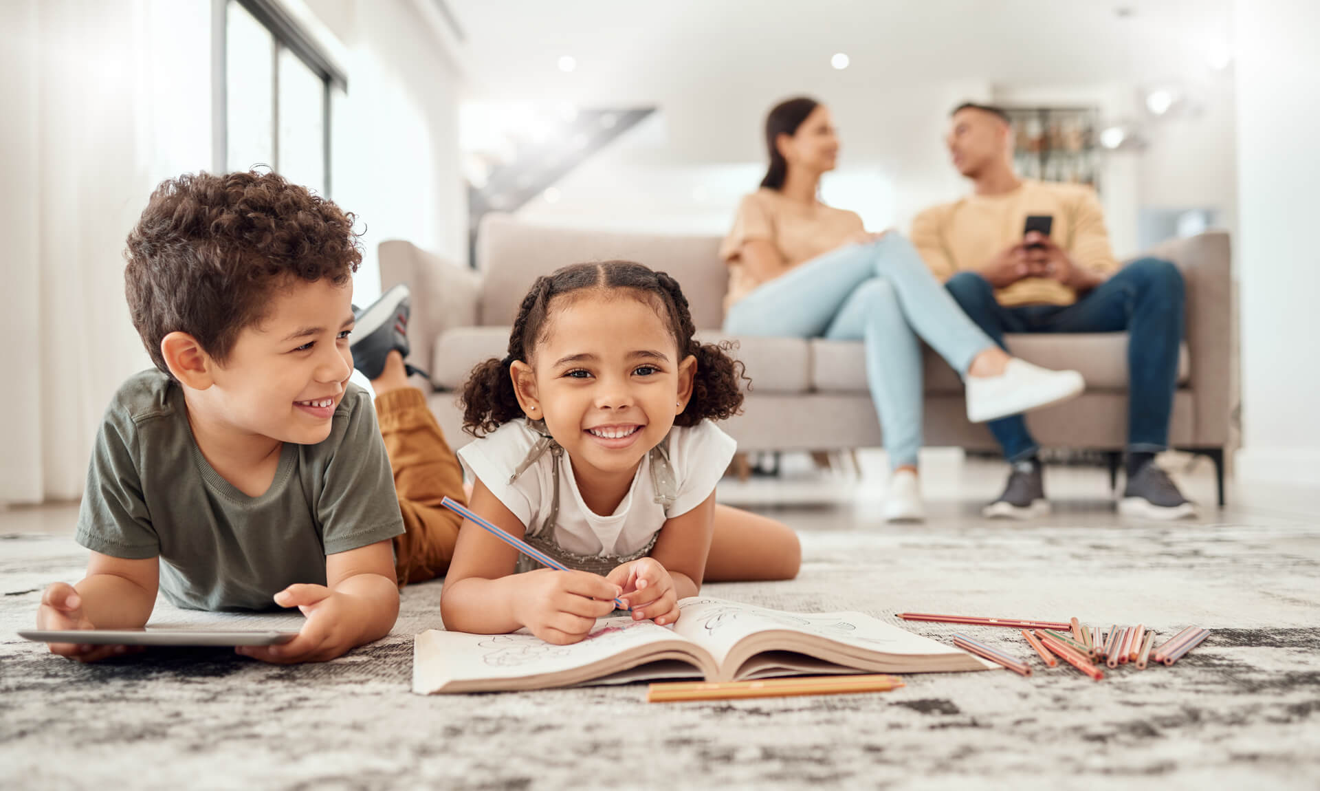 Family scene with kids playing on the floor, and parents relaxing on sofa in the background.