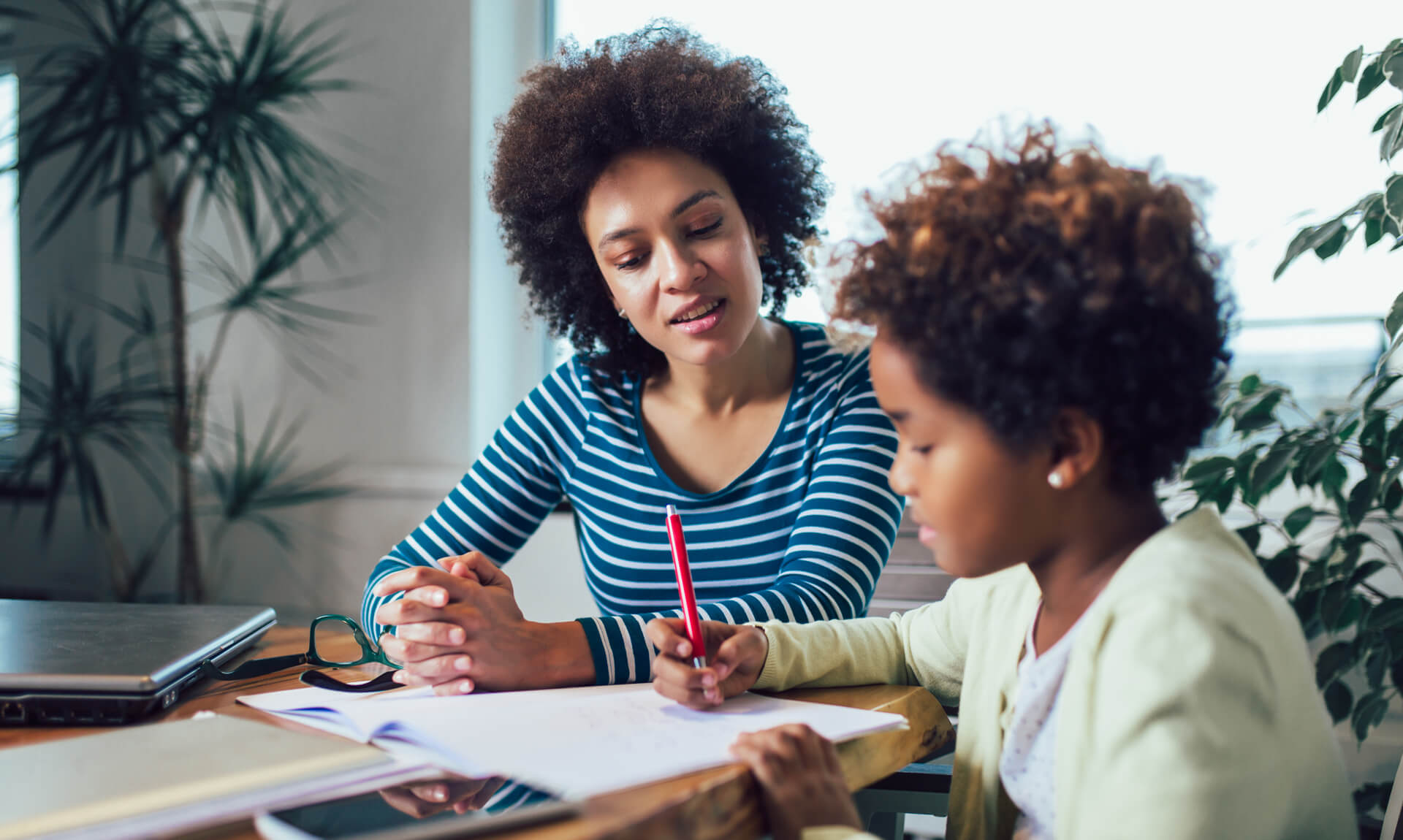 Mother helping her daughter at the table with homework.