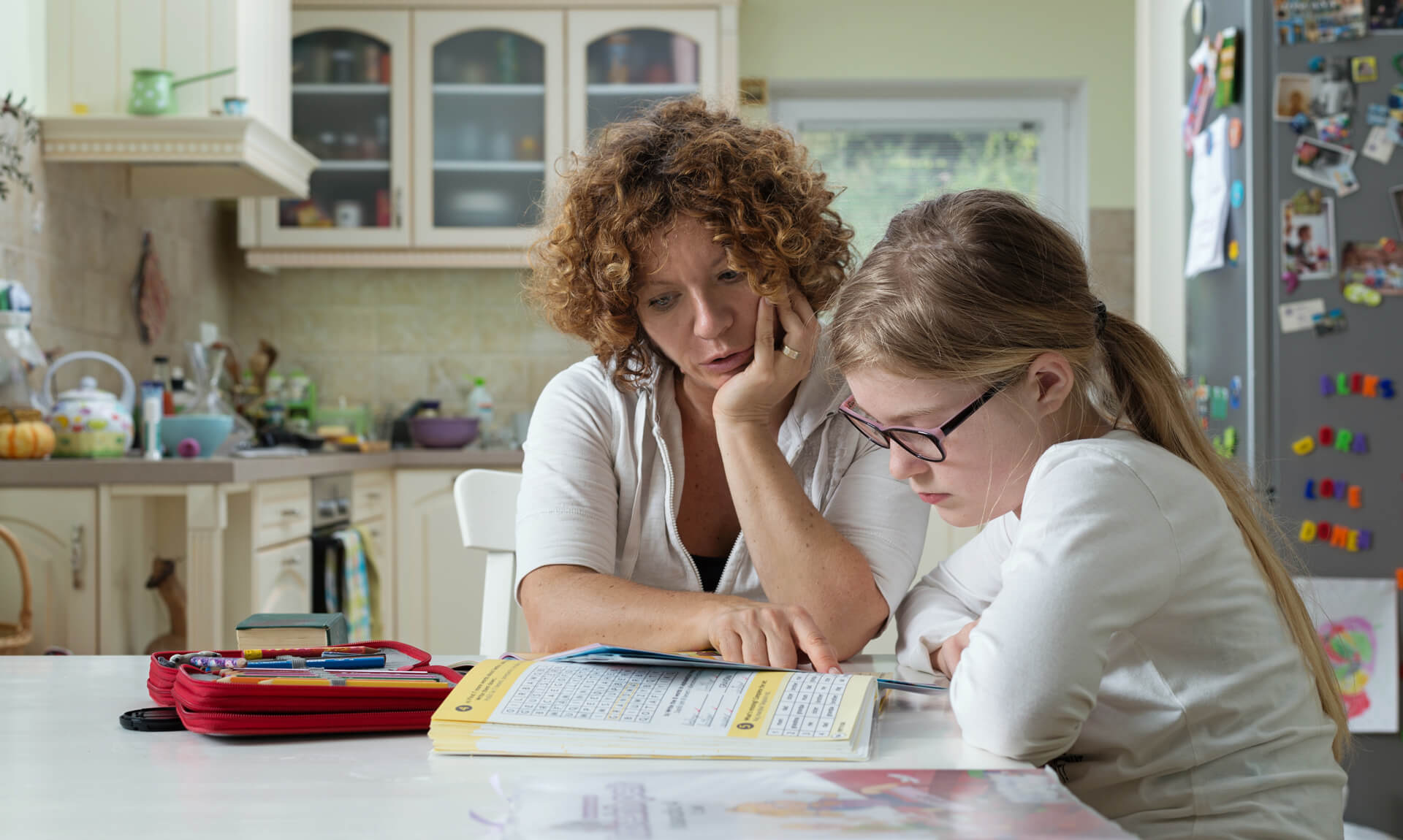 Special Education 101 and Dyslexia Mother helping daughter with her homework at the table in the dinning room.