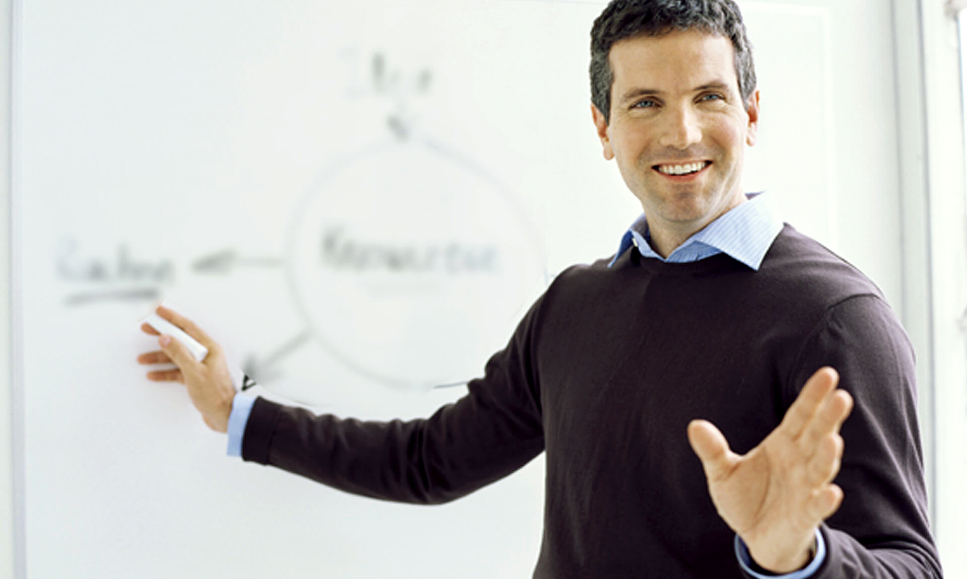 Teacher gestures to white board during lecture.