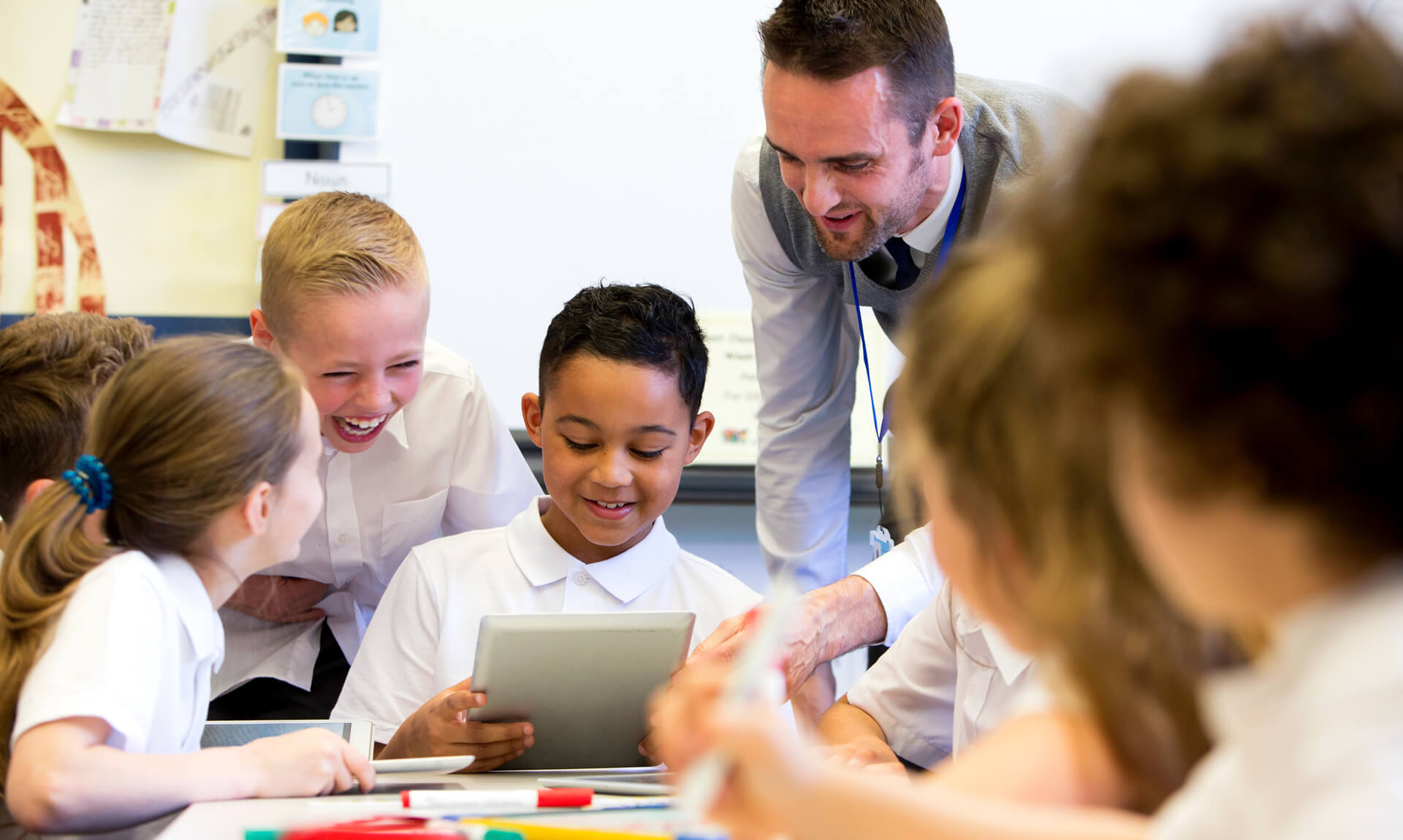 Happy teacher works with students in classroom.