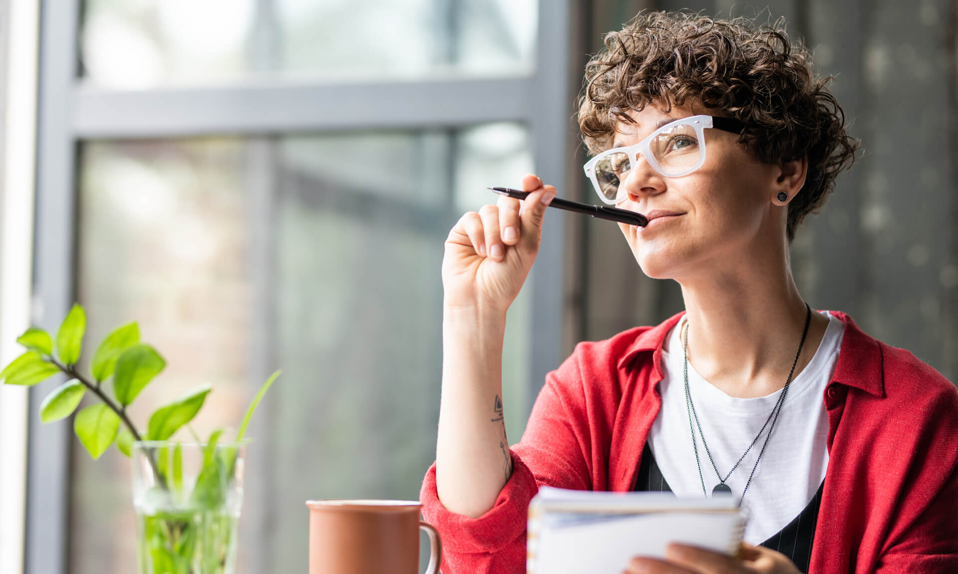 Young pensive female in eyeglasses thinking of new creative ideas
